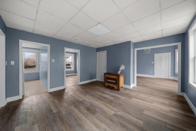 unfurnished living room featuring baseboards, wood finished floors, and a paneled ceiling