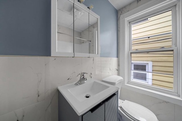 bathroom featuring a wealth of natural light, a marble finish shower, toilet, and vanity