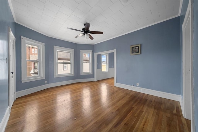 unfurnished room with a ceiling fan, crown molding, baseboards, and wood finished floors