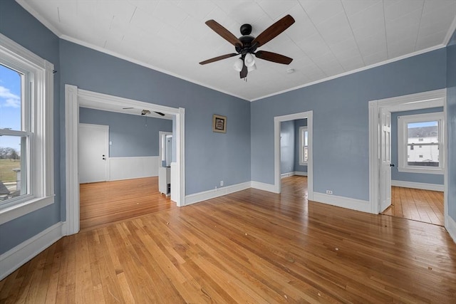 empty room featuring a ceiling fan, crown molding, baseboards, and light wood-style flooring