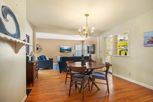 dining room with a chandelier, light wood-style floors, and baseboards