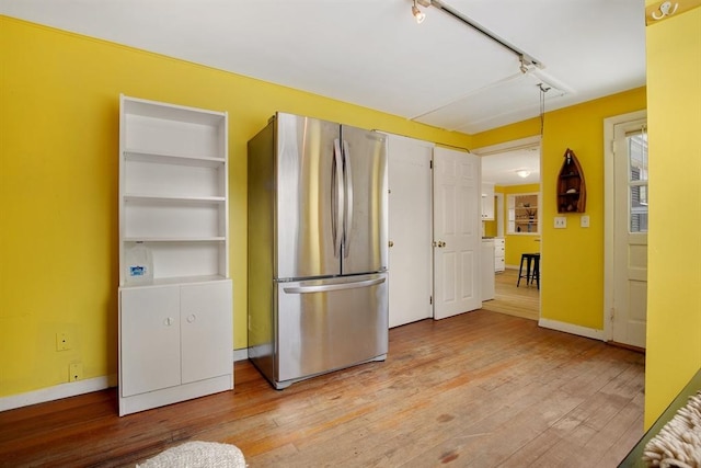 kitchen featuring light wood-type flooring, freestanding refrigerator, track lighting, and baseboards