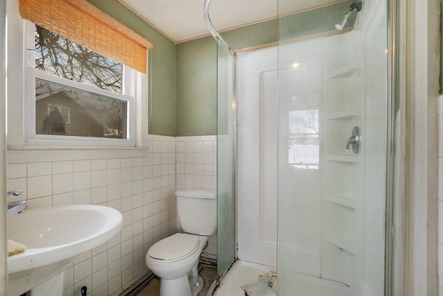 full bathroom featuring tile walls, toilet, a wainscoted wall, walk in shower, and a sink