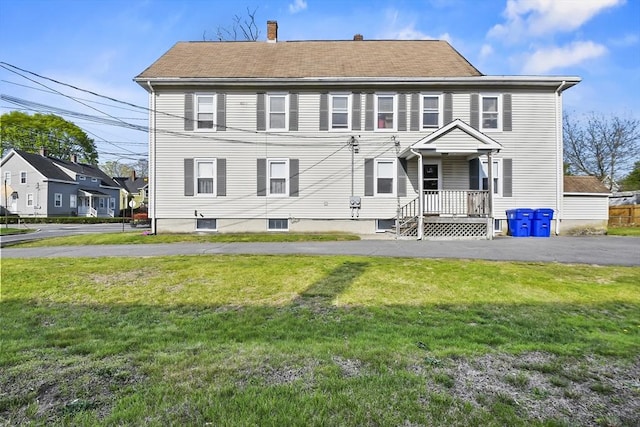 view of front of home with a front lawn, a chimney, and roof with shingles