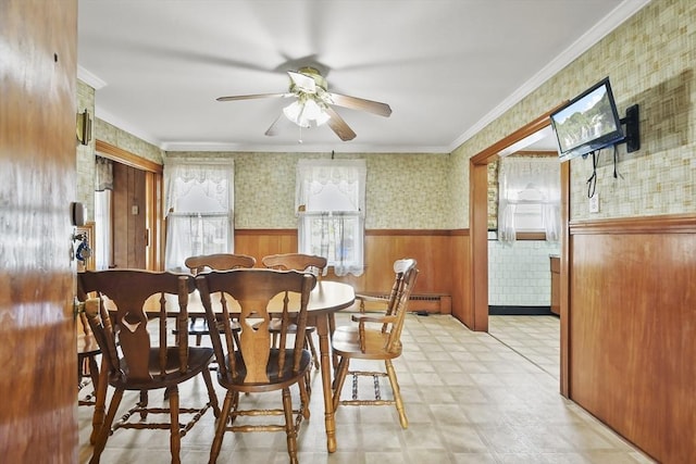 dining area with wainscoting, light flooring, ceiling fan, wallpapered walls, and crown molding