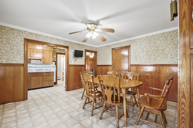 dining room featuring a wainscoted wall, ceiling fan, light flooring, wood walls, and wallpapered walls