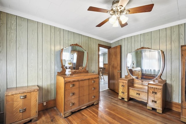 bedroom with crown molding, dark wood-style flooring, and wooden walls