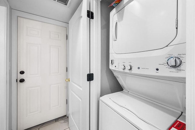 laundry area with stacked washer / drying machine and light marble finish floors