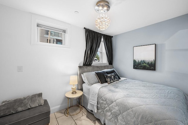 bedroom featuring a chandelier, light marble finish flooring, and baseboards