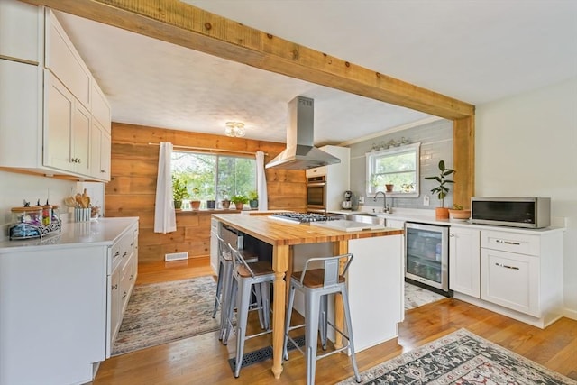 62 Greenbrier Dr, New Bedford, MA 02745 - kitchen with beverage cooler, island range hood, butcher block counters, light wood-style flooring, and white cabinets