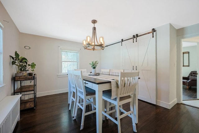 dining space featuring a barn door, dark wood-style flooring, and baseboards