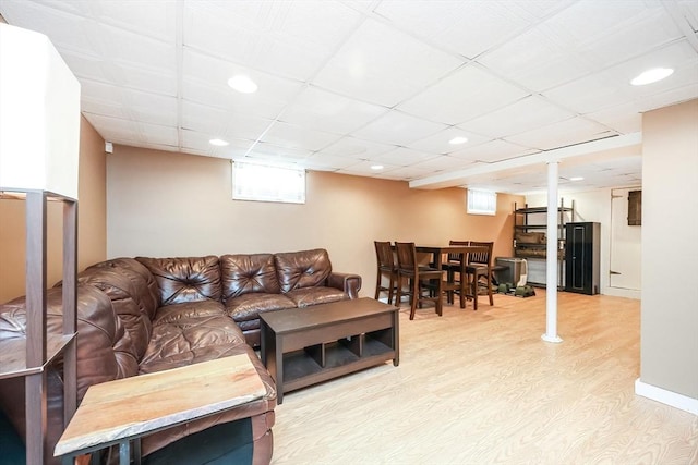 living area with light wood-type flooring, a paneled ceiling, and recessed lighting