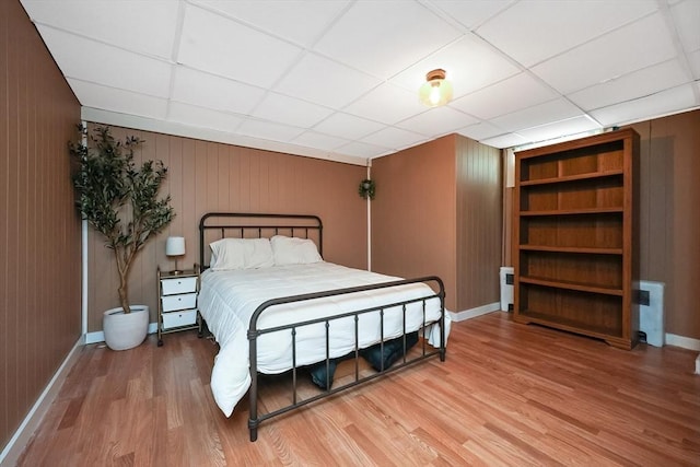 bedroom featuring a paneled ceiling, baseboards, and wood finished floors