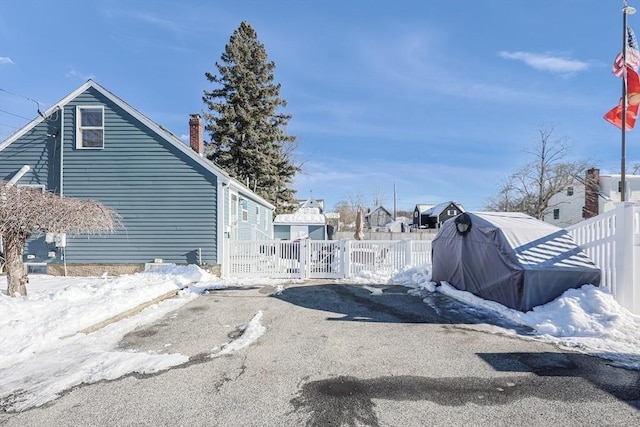 view of snowy exterior with a chimney and fence