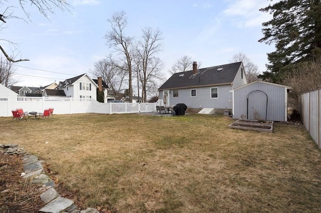 view of yard featuring a storage shed, a fenced backyard, and an outdoor structure