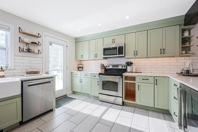 kitchen with open shelves, green cabinetry, stainless steel appliances, and light countertops