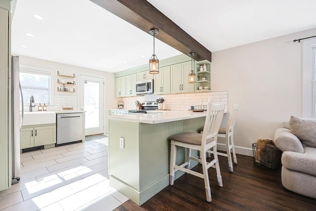 kitchen featuring open shelves, stainless steel appliances, light countertops, and a kitchen breakfast bar