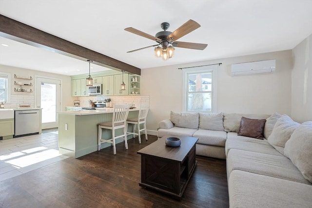 living room featuring an AC wall unit, dark wood-type flooring, beamed ceiling, and a healthy amount of sunlight