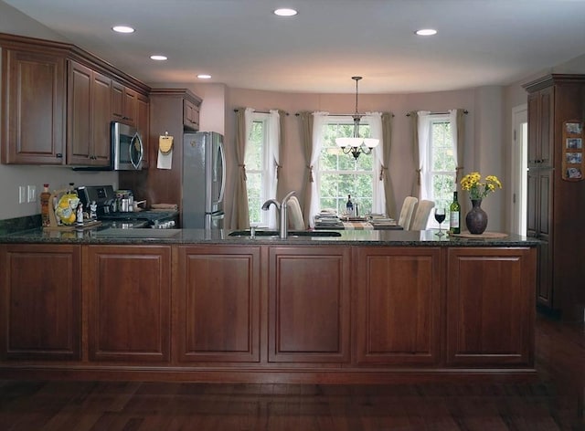 4 Bluebird Ln Unit 4, Killingly, CT 06241 - kitchen with stainless steel appliances, a sink, a peninsula, dark stone counters, and hanging light fixtures