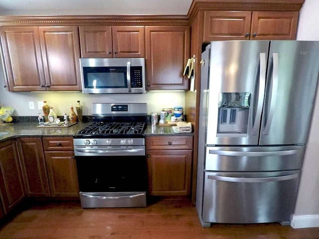 4 Bluebird Ln Unit 4, Killingly, CT 06241 - kitchen with appliances with stainless steel finishes, wood finished floors, brown cabinetry, and dark stone countertops