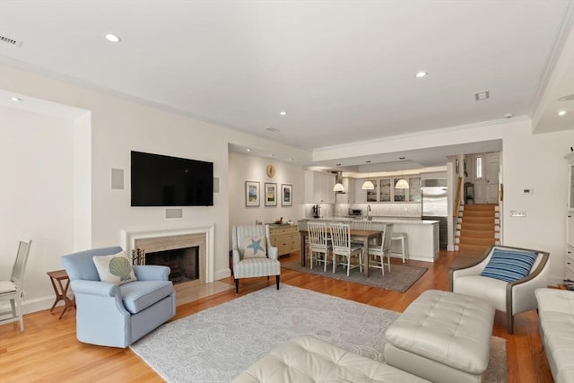 living area featuring light wood finished floors, a fireplace with flush hearth, recessed lighting, and baseboards