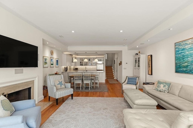 living room with recessed lighting, light wood-style flooring, a fireplace, and stairway