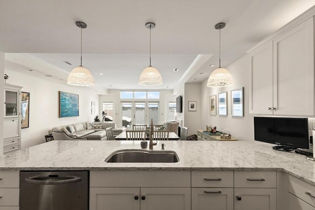 kitchen with light stone countertops, a sink, pendant lighting, stainless steel dishwasher, and open floor plan