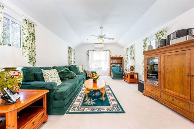 living area featuring vaulted ceiling, ceiling fan, a wealth of natural light, and light colored carpet