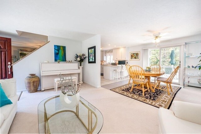 living room with a ceiling fan, light carpet, and baseboards