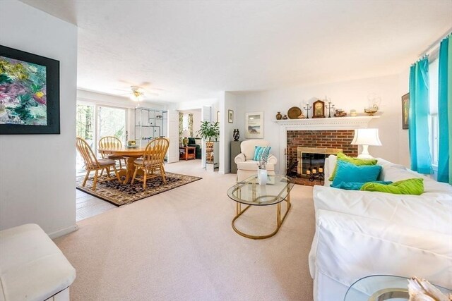 living area with a ceiling fan, a fireplace, and carpet