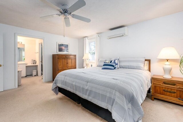 bedroom featuring a ceiling fan, light carpet, connected bathroom, and an AC wall unit