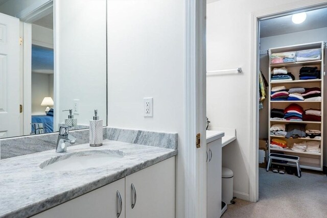 bathroom with vanity and a walk in closet