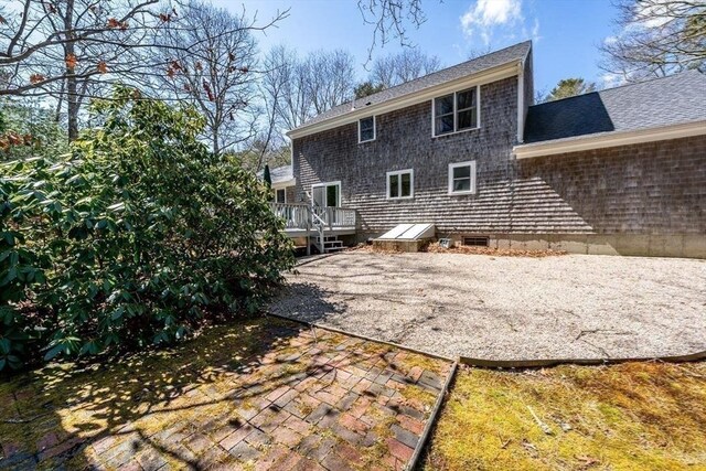 back of property featuring a deck, a shingled roof, and a patio area