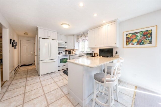 kitchen featuring a baseboard radiator, a breakfast bar, light countertops, white appliances, and a peninsula
