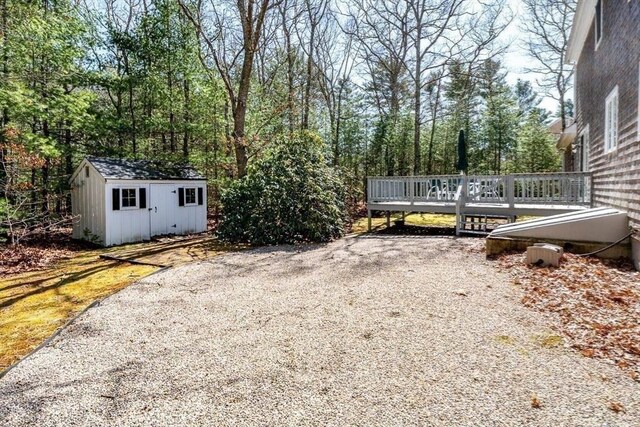 view of yard with a storage unit, a deck, and an outbuilding