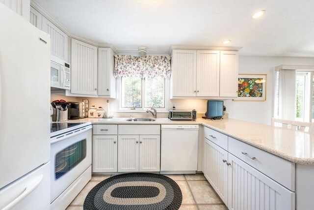 kitchen featuring a wealth of natural light, white appliances, a peninsula, and a sink