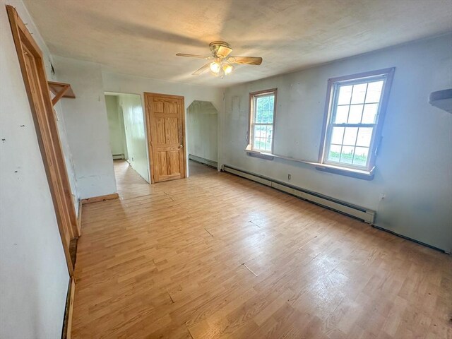 233 Grove St, Woonsocket, RI 02895 - unfurnished bedroom with baseboard heating, light wood-type flooring, a ceiling fan, arched walkways, and baseboards