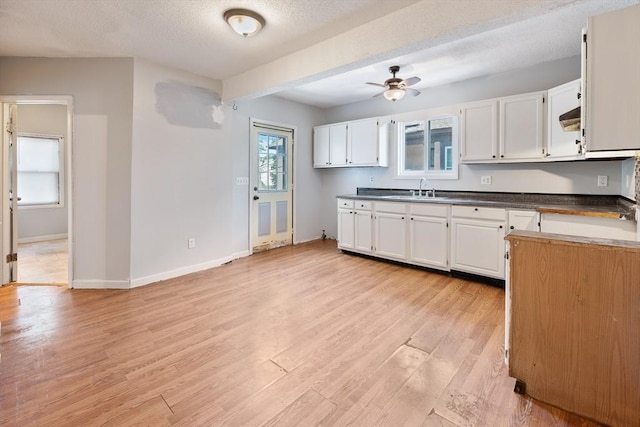 72 Hall St, Springfield, MA 01108 - kitchen with a ceiling fan, white cabinets, light wood-type flooring, dark countertops, and a textured ceiling