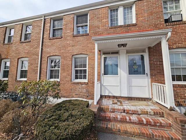 view of exterior entry featuring brick siding and cooling unit