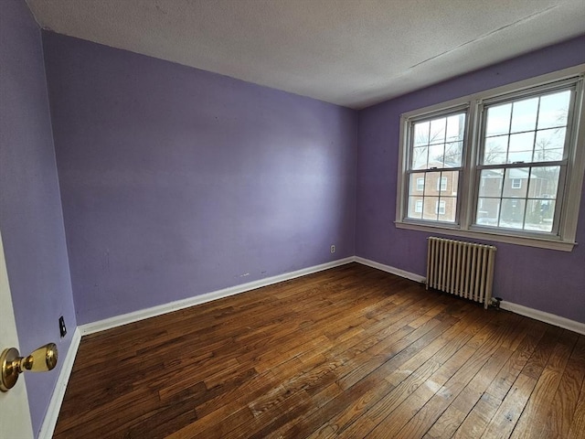 empty room with radiator heating unit, a textured ceiling, baseboards, and dark wood-style flooring