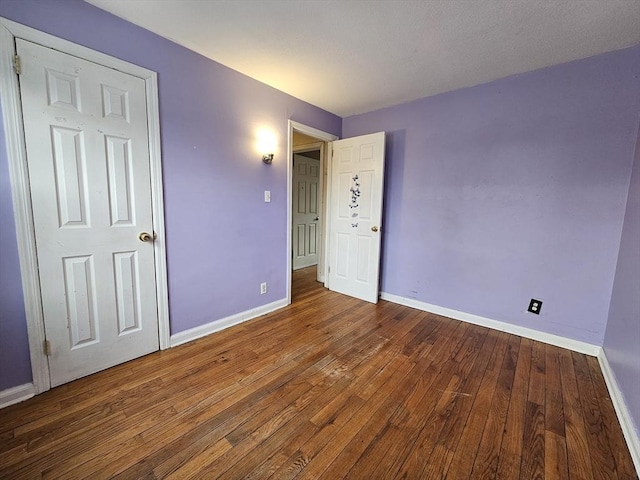 empty room featuring wood-type flooring and baseboards