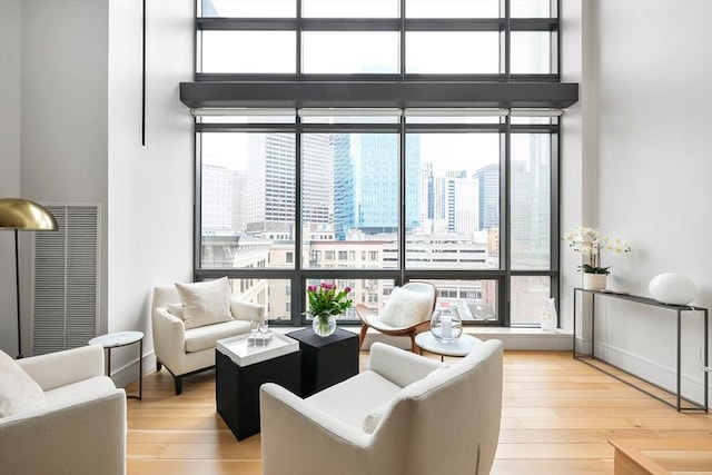 living area with light wood-style floors, a high ceiling, and a city view