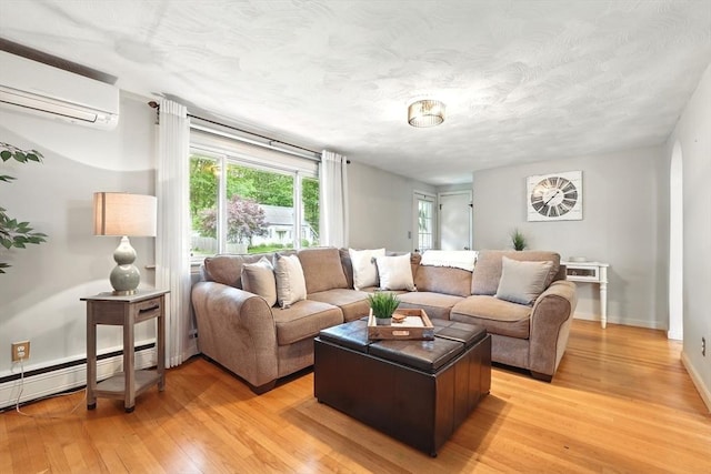 116 Anthony St, Agawam, MA 01001 - living room with a wall mounted air conditioner, light wood-style floors, a baseboard radiator, baseboards, and a textured ceiling