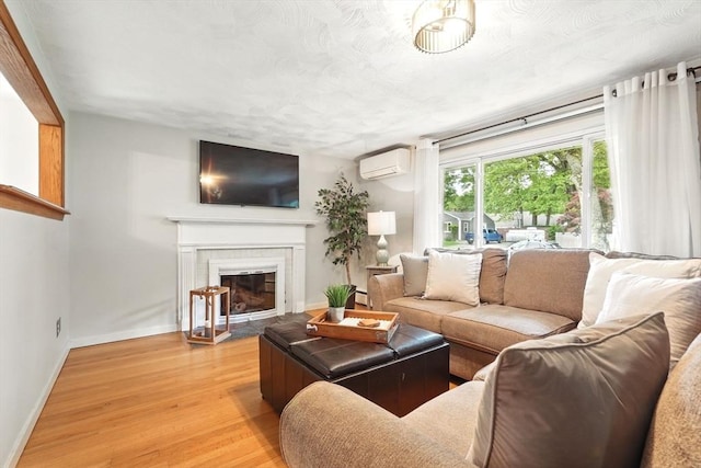 116 Anthony St, Agawam, MA 01001 - living room with a wall mounted AC, light wood finished floors, baseboards, a fireplace with flush hearth, and a baseboard heating unit