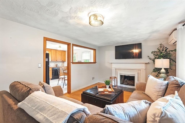 116 Anthony St, Agawam, MA 01001 - living room with light wood-style flooring, a wall mounted AC, a glass covered fireplace, and baseboards