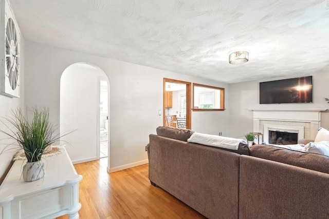 116 Anthony St, Agawam, MA 01001 - living area with arched walkways, light wood-type flooring, a glass covered fireplace, baseboards, and a textured ceiling