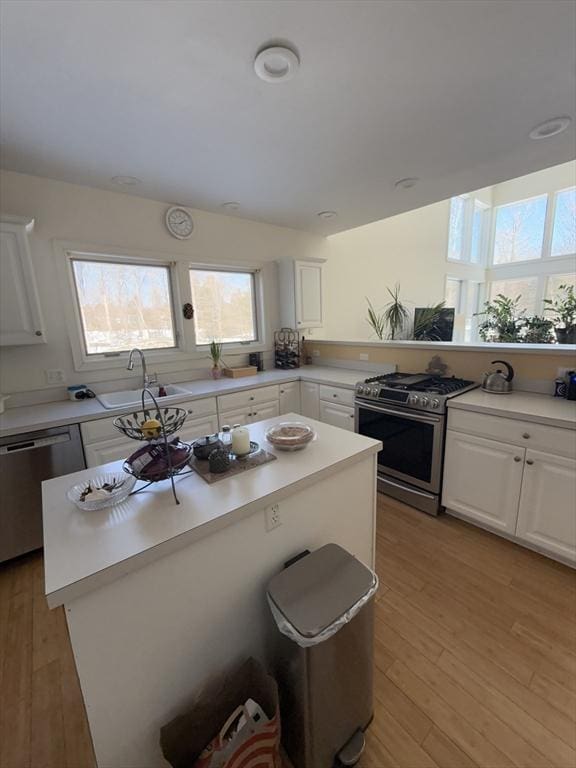 kitchen with a center island, light countertops, appliances with stainless steel finishes, white cabinetry, and a sink