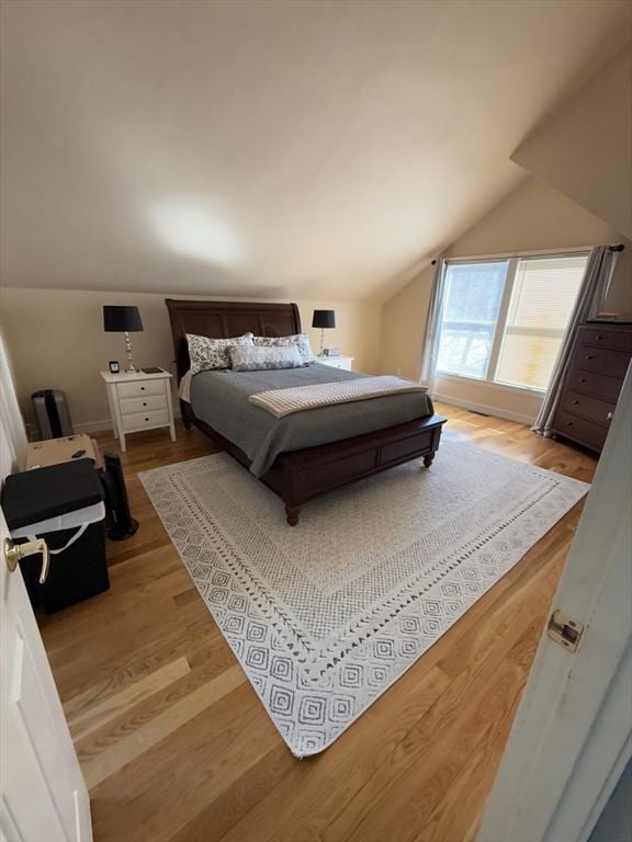 bedroom featuring light wood-style floors and vaulted ceiling