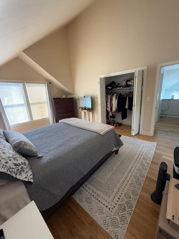 bedroom featuring light wood-type flooring, high vaulted ceiling, and a closet