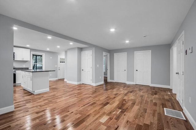 kitchen with white cabinets, a center island, and light hardwood / wood-style floors